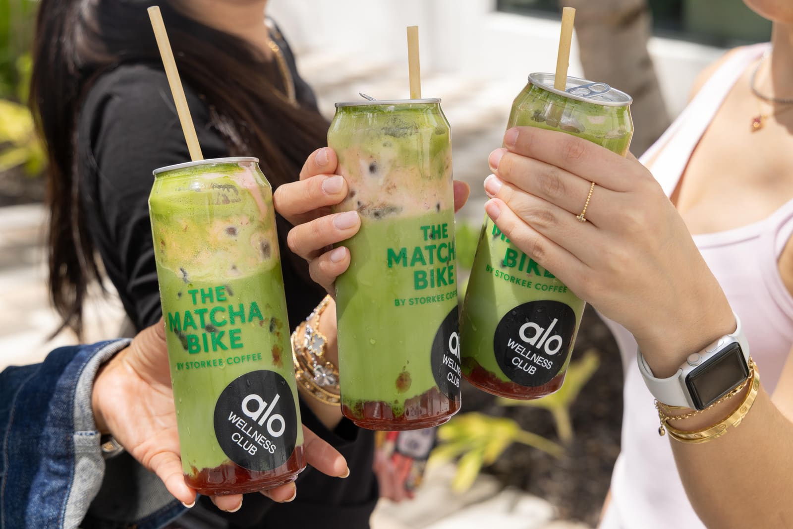 Three iced matcha cans clinking in a cheers