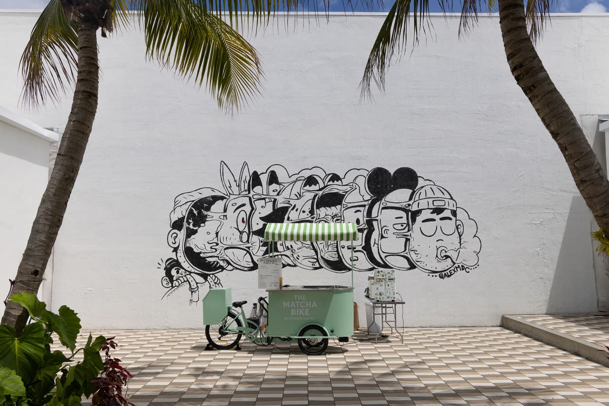 The mint cart under palms in front of the mural wall